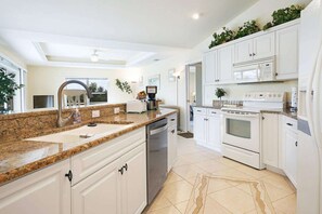 A modern kitchen with white cabinetry, granite countertops, a built-in oven, and a microwave. - Villa Cimarron - Waterfront Pool Home, Kayaks & Bikes (Cape Coral)