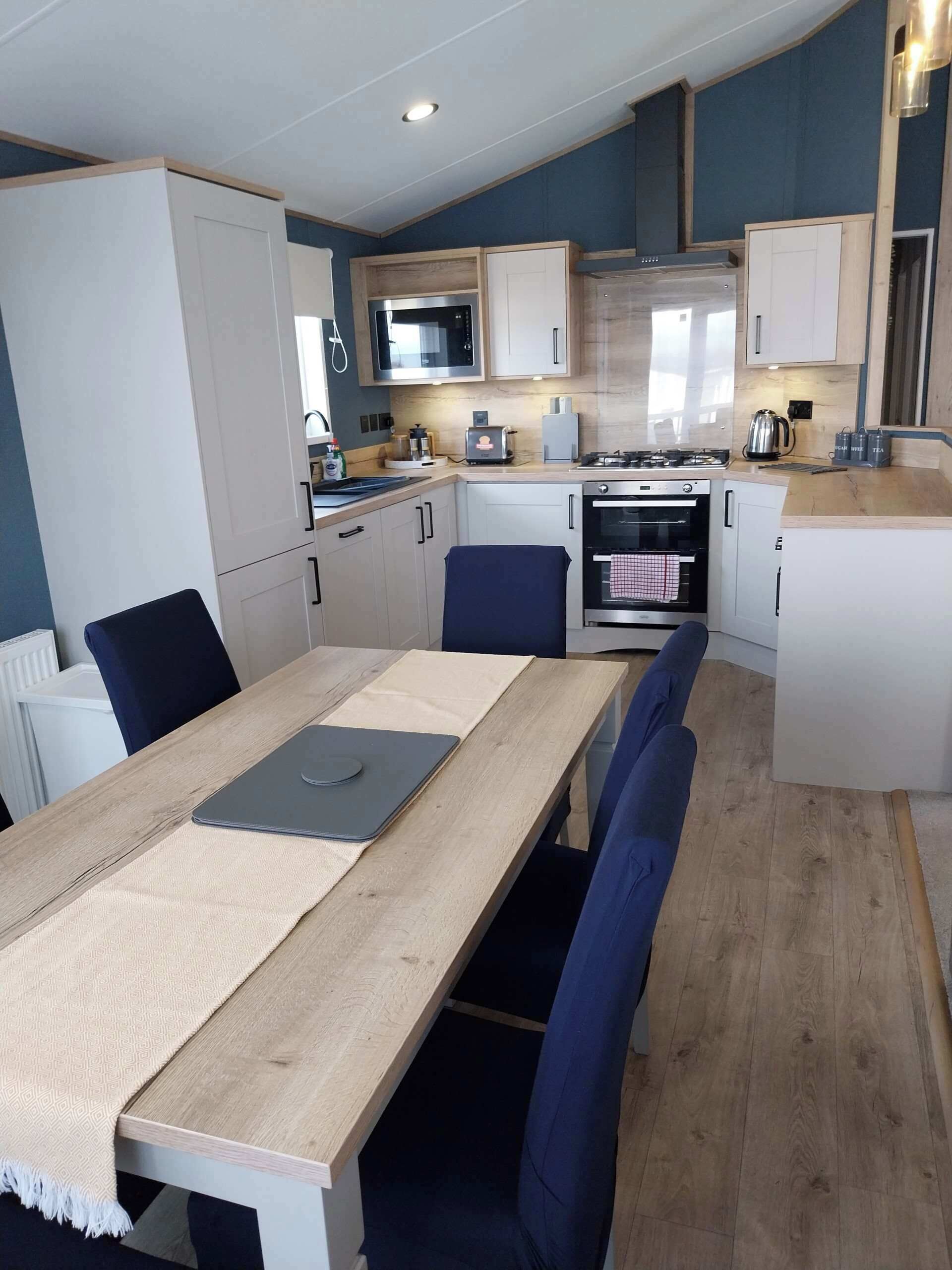 A compact kitchen with a dining area, featuring a microwave, stove, and cabinets.