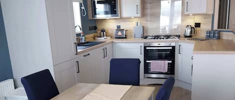 A compact kitchen with a dining area, featuring a microwave, stove, and cabinets.