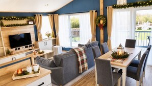 A cozy living area with a sofa, dining table, and TV. - Kielder - Spacious 3 Bed, Luxury Lodge, Haven, Seton Sands (Port Seton)