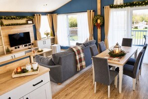 A cozy living area with a sofa, dining table, and TV. - Kielder - Spacious 3 Bed, Luxury Lodge, Haven, Seton Sands (Port Seton)