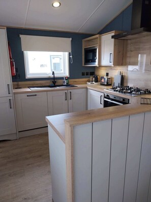 A modern kitchen with a central island, built-in microwave, and stainless steel appliances. - Kielder - Spacious 3 Bed, Luxury Lodge, Haven, Seton Sands (Port Seton)