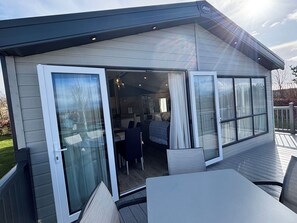 Ein modernes Haus mit einer überdachten Terrasse, komplett mit Esstisch und Stühlen.