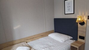 A neatly made bed with a headboard, a bedside table with a lamp, and a framed picture on the wall. - Kielder - Spacious 3 Bed, Luxury Lodge, Haven, Seton Sands (Port Seton)