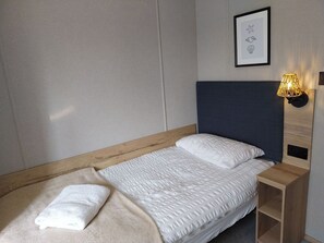 A neatly made bed with a headboard, a bedside table with a lamp, and a framed picture on the wall. - Kielder - Spacious 3 Bed, Luxury Lodge, Haven, Seton Sands (Port Seton)