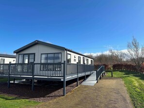 Ein Bungalow mit überdachter Veranda und einer Rampe zum Eingang.