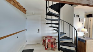 A spiral staircase with a black metal railing, a door with a white frame, and a small table with a patterned tablecloth. - NEW! Cozy escape with breathtaking treetop views (Silverthorne)