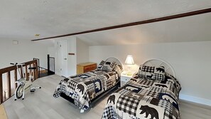 A bedroom with two beds, a nightstand, a lamp, a wooden chair, a desk, and a door. - NEW! Cozy escape with breathtaking treetop views (Silverthorne)