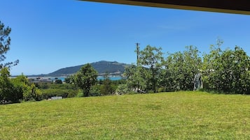 Espacio al aire libre con césped, árboles y vistas a una colina y un cuerpo de agua.