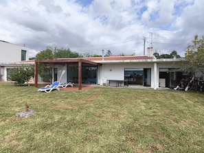 A modern house with a covered patio, a lawn, and a pool area.