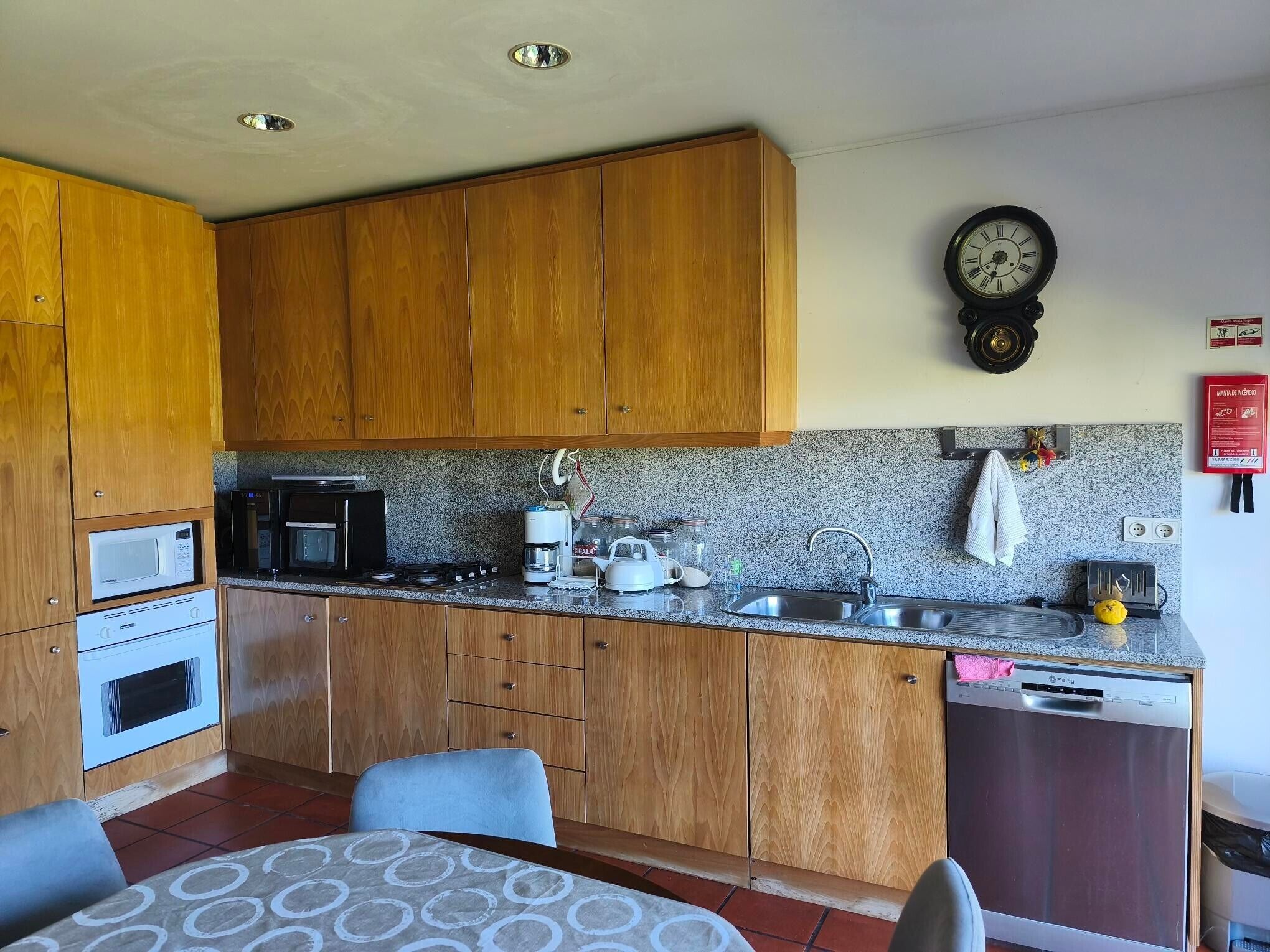 Cocina compacta con armarios de madera, microondas, cafetera y pileta.