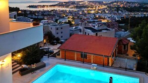 Un quartier résidentiel doté d’une piscine, d’un bâtiment à toit rouge et offrant une vue sur le paysage urbain au crépuscule.