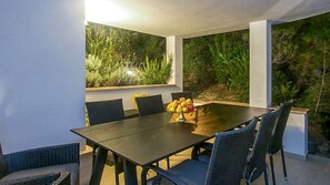 A dining area with a table, chairs, and a fruit bowl.