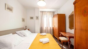 Une chambre d’hôtel comprenant un lit, un bureau, une chaise, une armoire et un miroir.