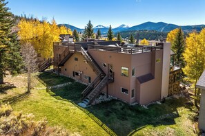 A multi-story building with a staircase, outdoor seating, and a view of mountains. - Panoramic rooftop deck, captivating views, and tranquil luxury (Dillon)