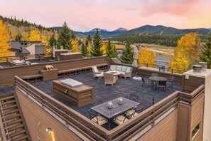 Eine Dachterrasse mit Gartenmöbeln, einem Feuerkorb und Blick auf die Berge.