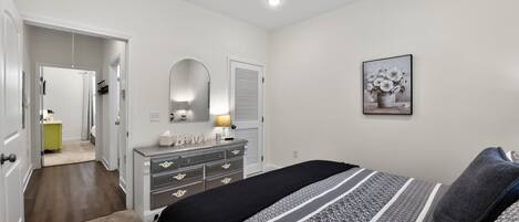 Ein Schlafzimmer mit Bett, Kommode, Spiegel und Deckenventilator.