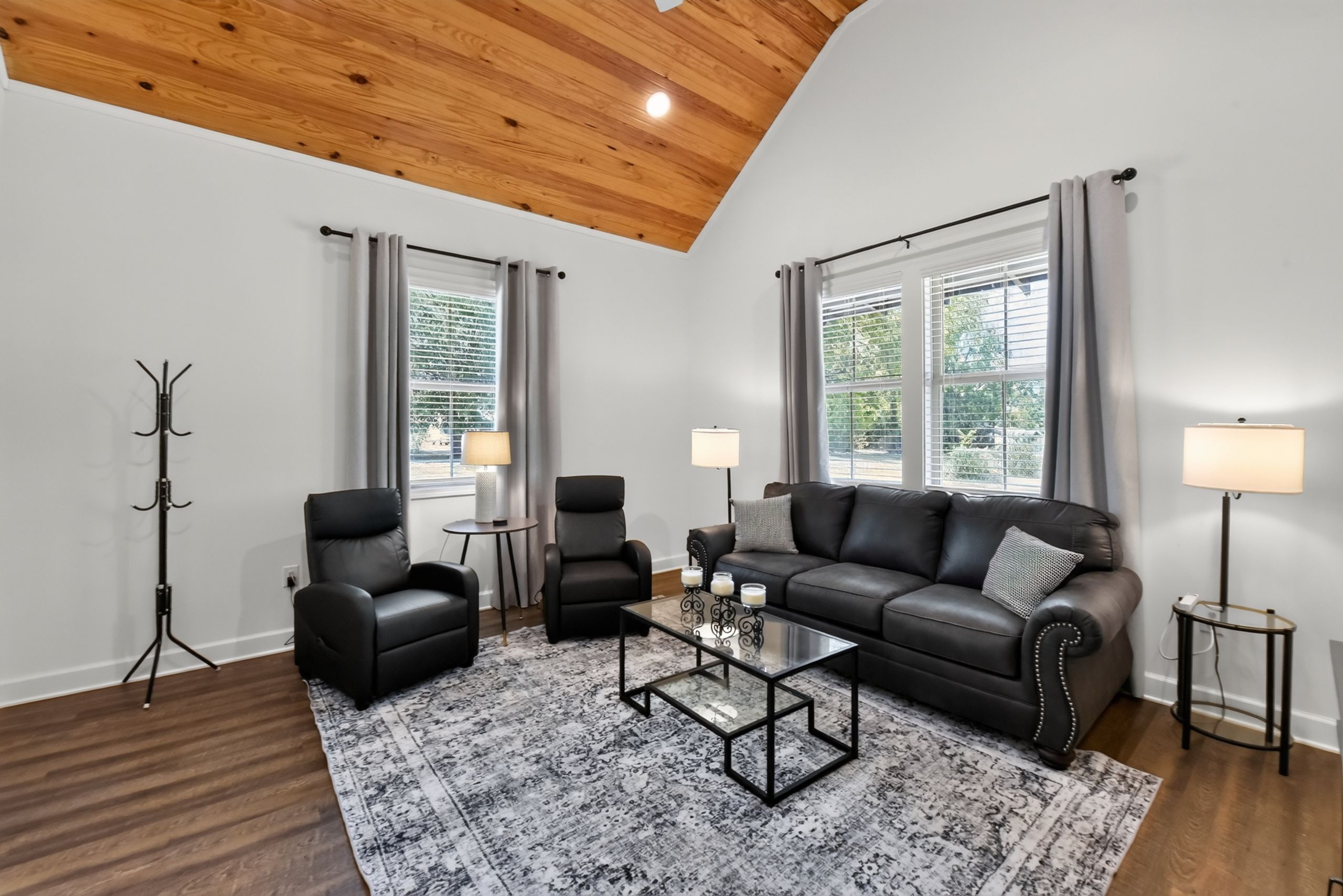 Un salon moderne avec un canapé en cuir noir, deux fauteuils, une table basse et un lampadaire.