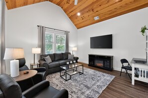 Una sala de estar moderna con chimenea, sofá de cuero y televisor de pantalla plana.