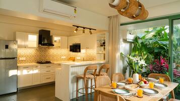 A modern kitchen with white cabinets, a central island, and a dining area with a table set for breakfast.