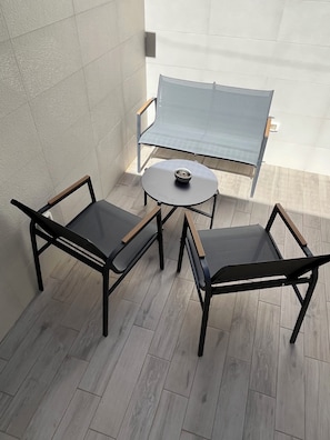 A small outdoor seating area with a round table and two chairs, a blue folding table, and a wall-mounted light fixture. - Cozy, self-contained apartment just a few minutes from the historic center of Lecce (Lecce)