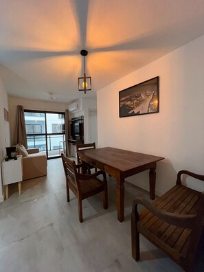 A modern living room with a dining table, chairs, a sofa, and a television. - BEACH WALKABLE Charming 2-bedroom apartment with AC in enchanting Rio (Rio de Janeiro)
