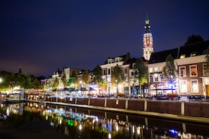 A riverside view of a historic town with illuminated buildings and a prominent tower.