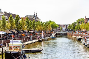A canal with boats docked, a boat named 'Rondvaart' with a small cabin, and buildings along the canal.