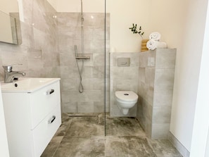 A modern bathroom with a shower, toilet, and sink.