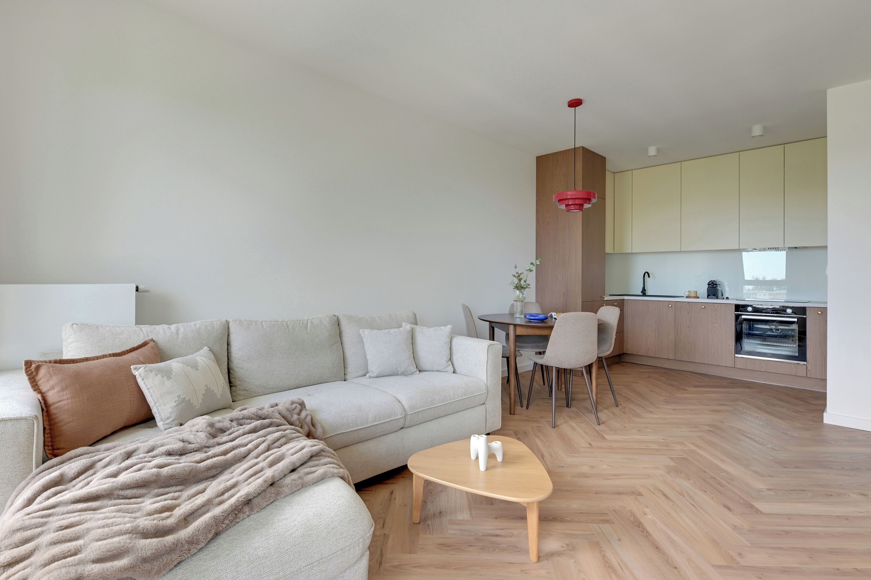 A modern living room with a sofa, coffee table, and a dining area with chairs.