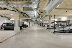 A multi-level parking garage with concrete pillars, metal railings, and cars parked on different levels.