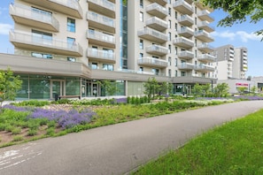 A modern building with multiple balconies and a landscaped garden area.