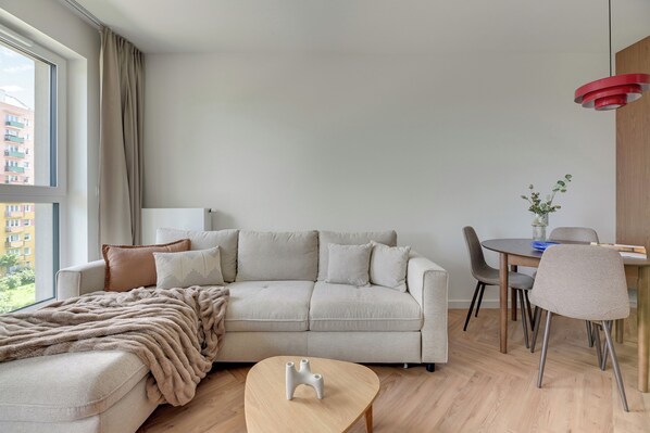 A modern living room with a sofa, a coffee table, and a dining area with chairs and a table.