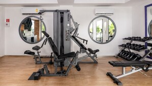 Een sportschool met trainingsapparatuur, spiegels en een dumbbellsrek.