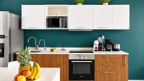 Een moderne keuken met witte kastjes, een roestvrijstalen koelkast, een magnetron, een koffiezetapparaat en een Siemens oven.