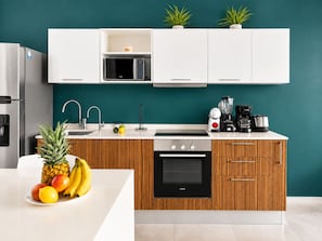A modern kitchen with white cabinets, a stainless steel refrigerator, a microwave, a coffee maker, and a Siemens oven. - One Bedroom Apartment (Playa Del Carmen)