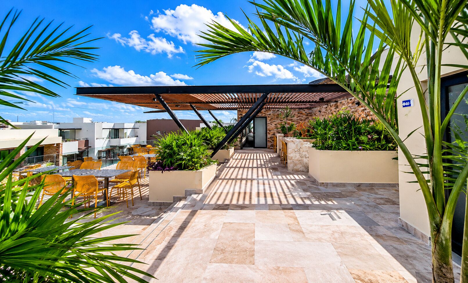 A rooftop terrace with outdoor seating, a covered walkway, and potted plants.