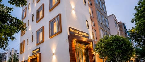 A multi-story hotel with a white facade, multiple windows, and a well-lit entrance.