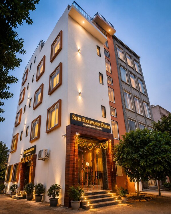 A multi-story hotel with a sign reading 'Shri Harivansh Dham Hospitality With Devotion.' - SHRI HARIVANSH DHAM (Mathura)