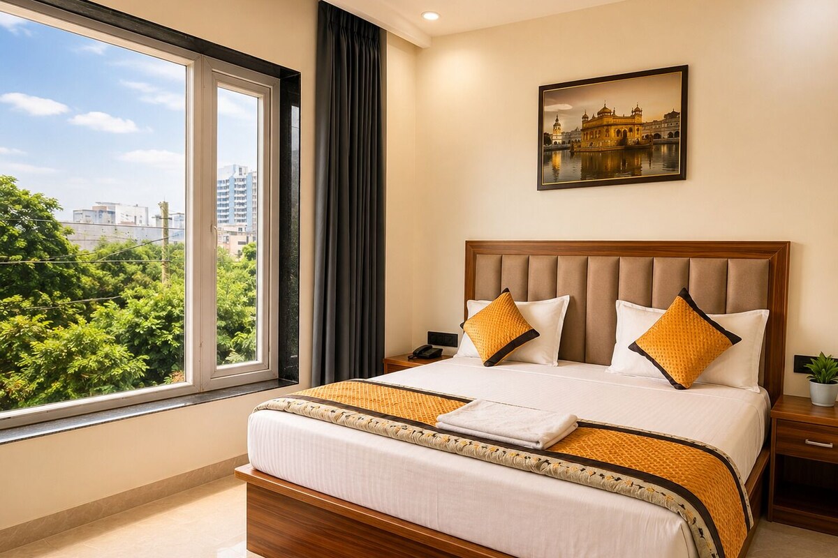 A hotel room with a large window, a bed with a wooden headboard, and a painting of a historical building.