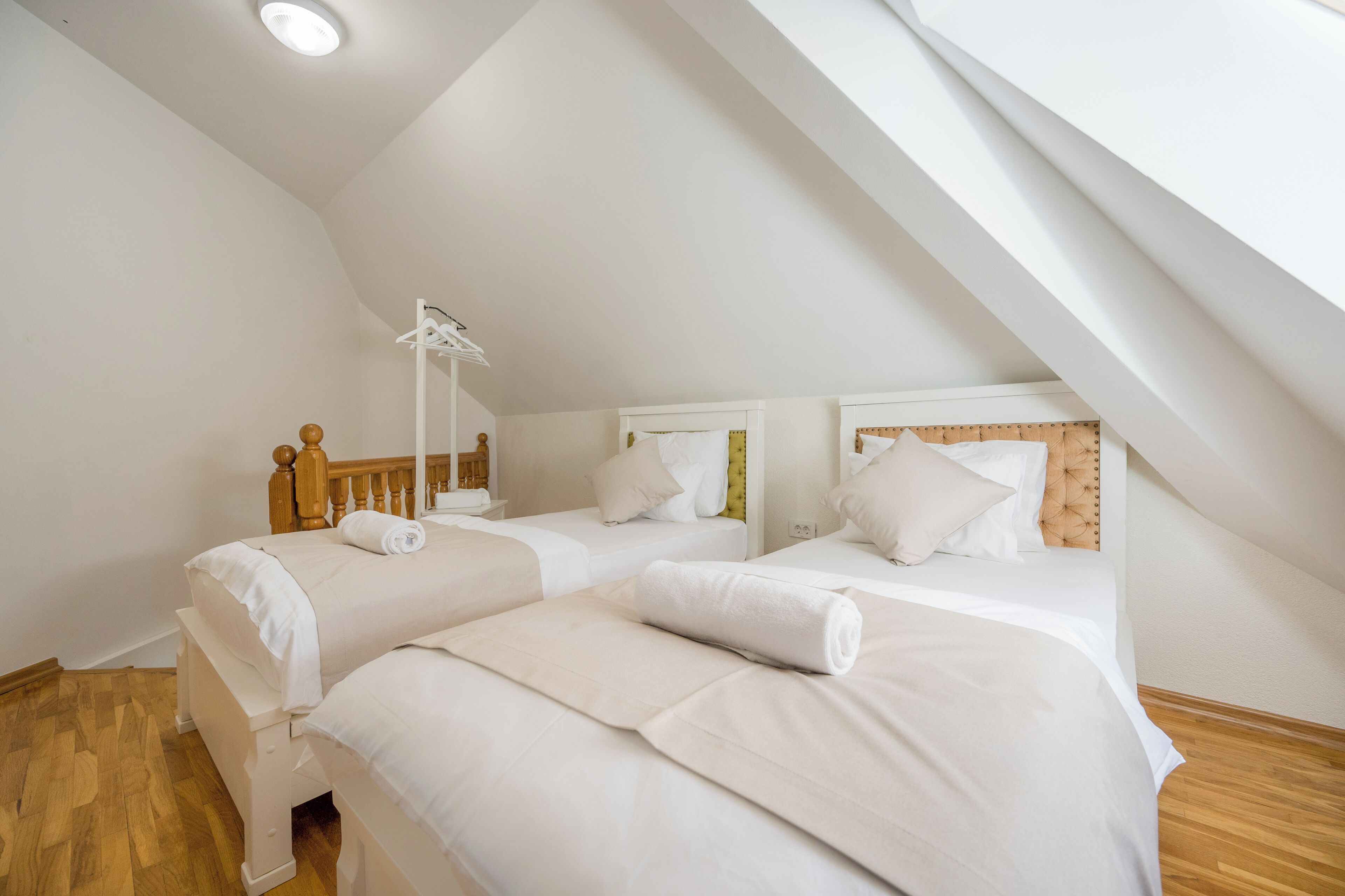 Ein Zimmer mit zwei Betten, Holz-Kopfteilen und einer weißen Decke.