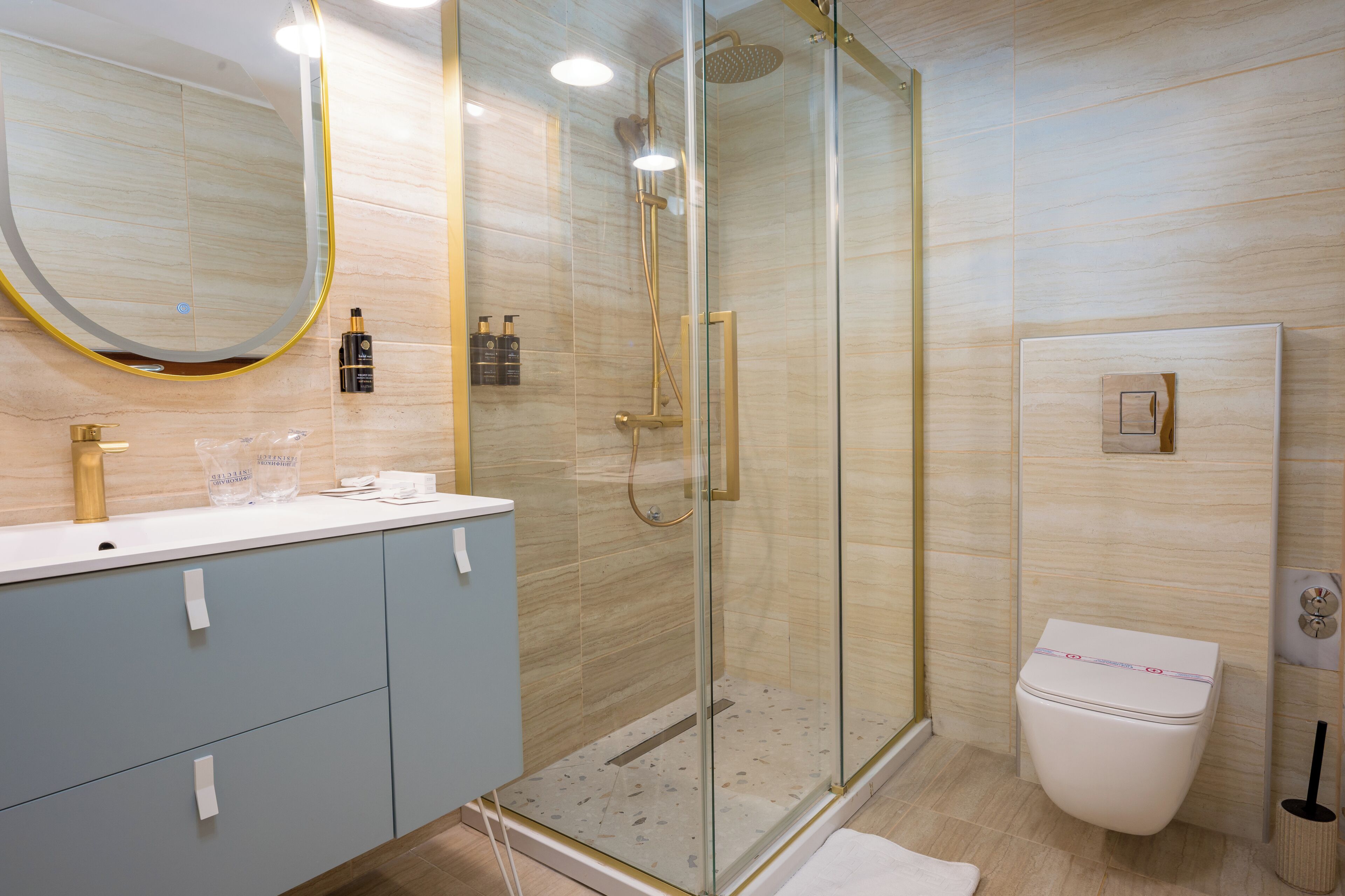 A modern bathroom with a glass-enclosed shower, a white toilet, and a vanity with a mirror.