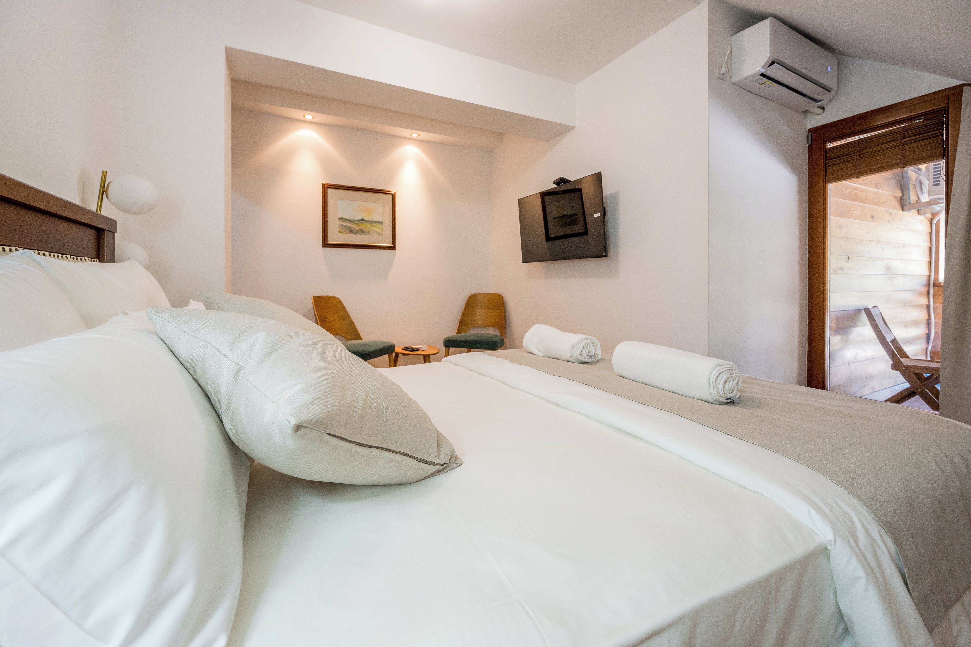 Una habitación de hotel con una cama grande, dos sillas, una mesita y un cuadro en la pared.