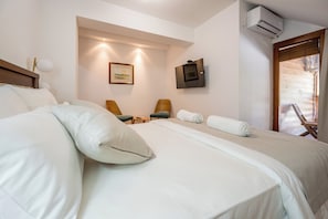 Una habitación de hotel con una cama grande, dos sillas, una mesita y un cuadro en la pared.