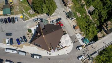 An aerial view of a parking lot with multiple cars and a building with a sloped roof.