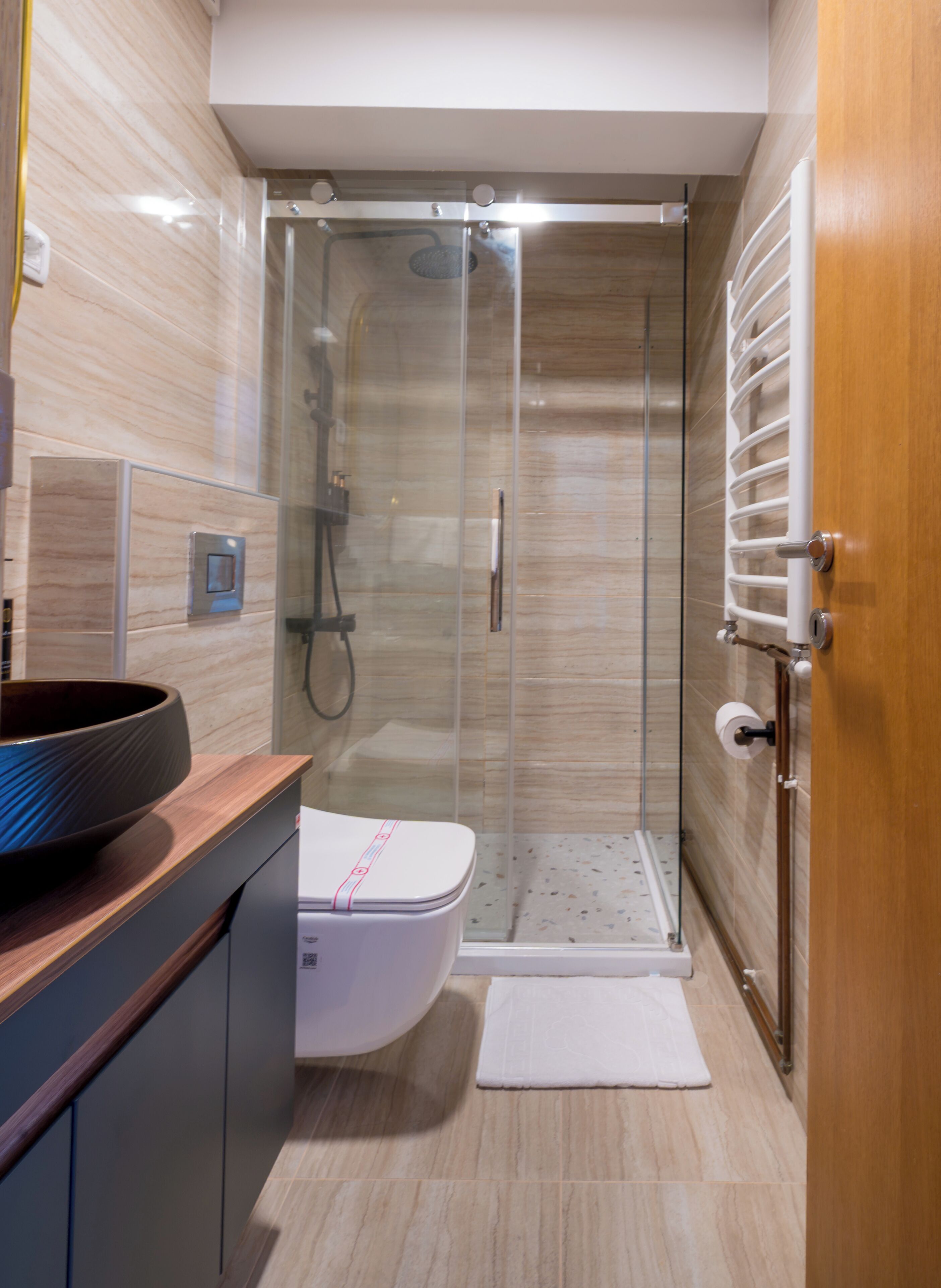 A modern bathroom with a glass shower enclosure, a white toilet, and a wooden vanity.