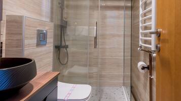 A modern bathroom with a glass shower enclosure, a white toilet, and a wooden vanity.