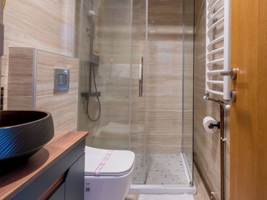 A modern bathroom with a glass shower enclosure, a white toilet, and a wooden vanity.