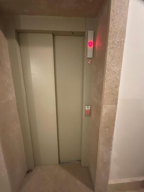 An elevator with a closed door, a no-smoking sign, and a button panel. - Terrific 3-bedroom apartment with AC and Free-Wifi in lovely Madinty Garden View (Madinaty)