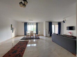 Un grand espace de vie comprenant une table à manger, des chaises, un canapé et un téléviseur.